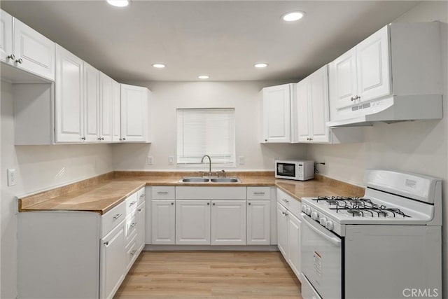 kitchen with white cabinets, light wood-type flooring, white appliances, and sink