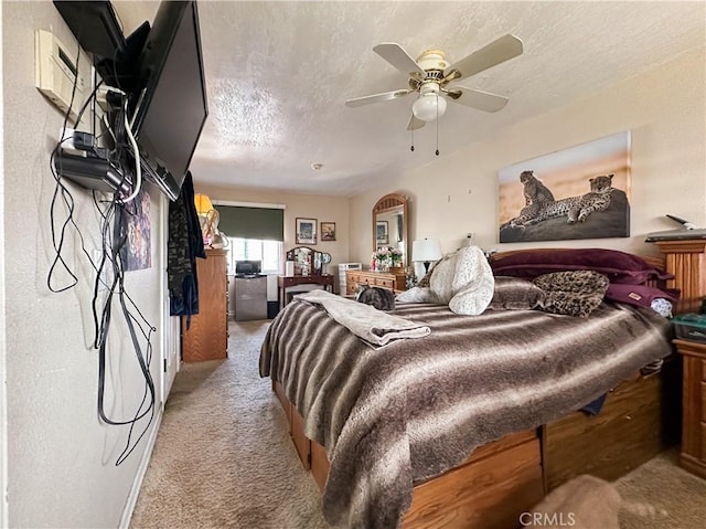 carpeted bedroom with ceiling fan and a textured ceiling