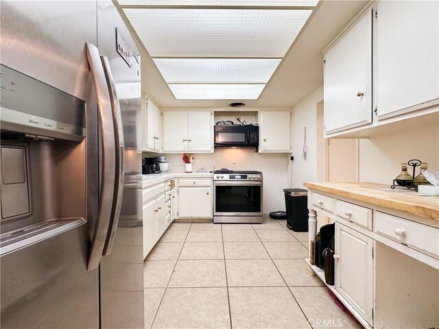 kitchen with stainless steel appliances, white cabinetry, and light tile patterned floors