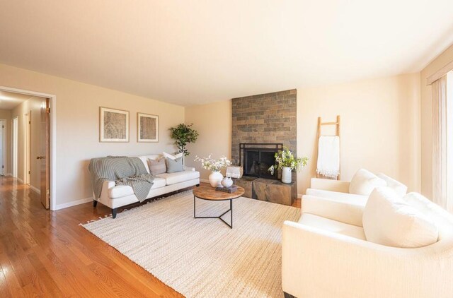 living room with a brick fireplace and wood-type flooring