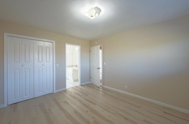 unfurnished bedroom featuring a closet, light hardwood / wood-style flooring, and ensuite bath