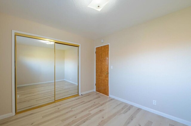 unfurnished bedroom with a closet and light hardwood / wood-style floors