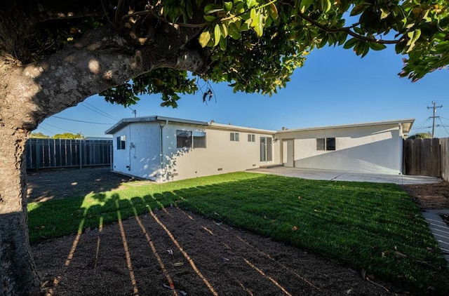 rear view of house featuring a lawn and a patio