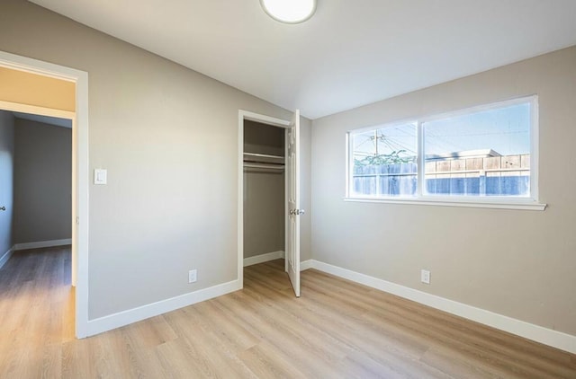 unfurnished bedroom with lofted ceiling, light hardwood / wood-style flooring, and a closet