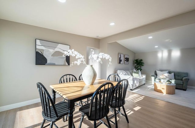 dining room with light hardwood / wood-style floors and vaulted ceiling with beams