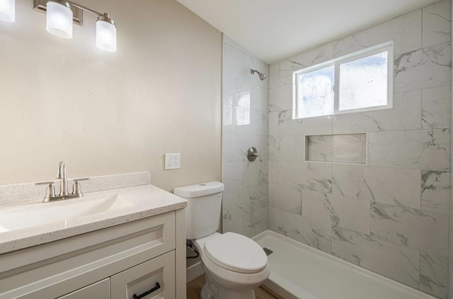 bathroom with vanity, toilet, and a tile shower