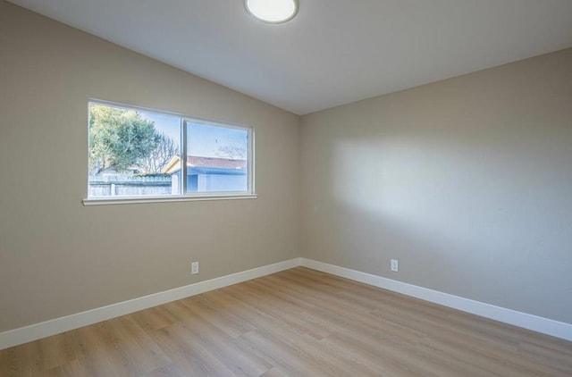 spare room with lofted ceiling and light hardwood / wood-style flooring