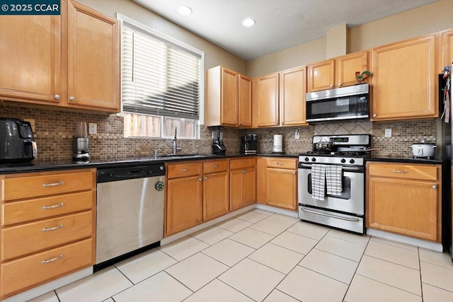 kitchen with decorative backsplash, appliances with stainless steel finishes, sink, and light tile patterned flooring