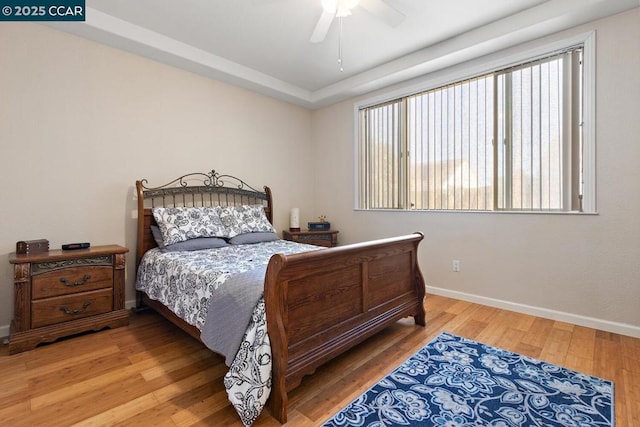 bedroom with ceiling fan, multiple windows, and hardwood / wood-style flooring