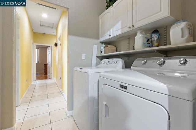 laundry room featuring light tile patterned floors, washing machine and dryer, and cabinets