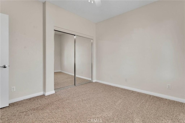 unfurnished bedroom with ceiling fan, a closet, and carpet flooring