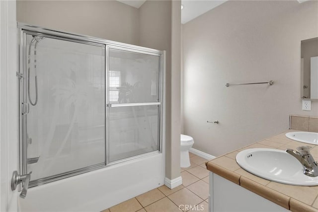 full bathroom featuring toilet, bath / shower combo with glass door, tile patterned floors, and vanity