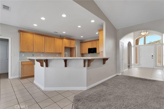 kitchen featuring light tile patterned floors, a kitchen bar, and backsplash