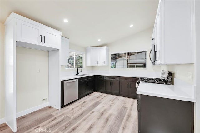 kitchen featuring lofted ceiling, sink, white cabinetry, light hardwood / wood-style flooring, and appliances with stainless steel finishes