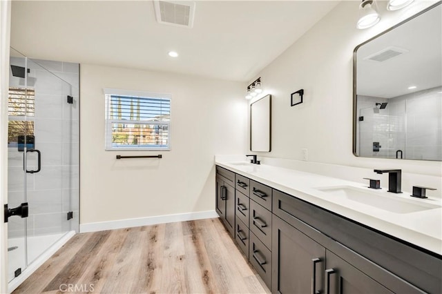 bathroom with a shower with door, wood-type flooring, and vanity