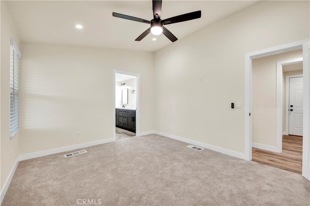 unfurnished bedroom with vaulted ceiling, ceiling fan, light colored carpet, and ensuite bath