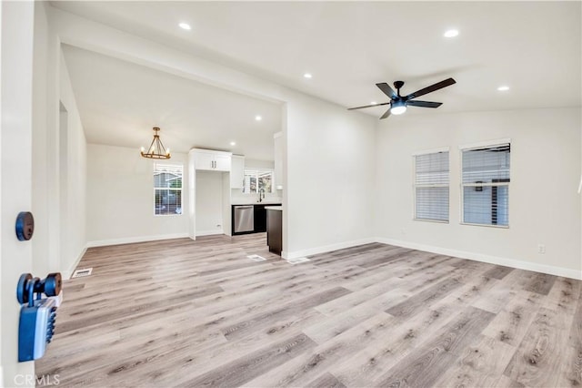 unfurnished living room featuring light wood-type flooring, lofted ceiling, and ceiling fan with notable chandelier