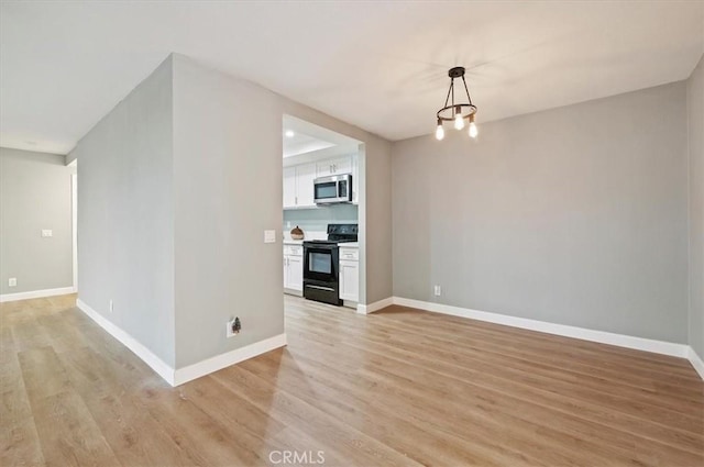 unfurnished living room with light wood-type flooring and a notable chandelier