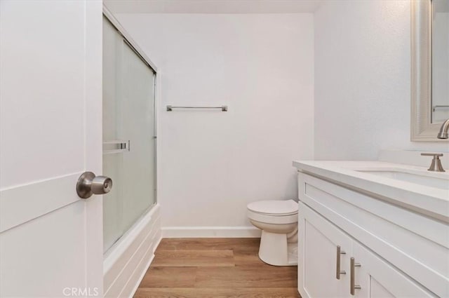 full bathroom with toilet, hardwood / wood-style flooring, vanity, and shower / bath combination with glass door