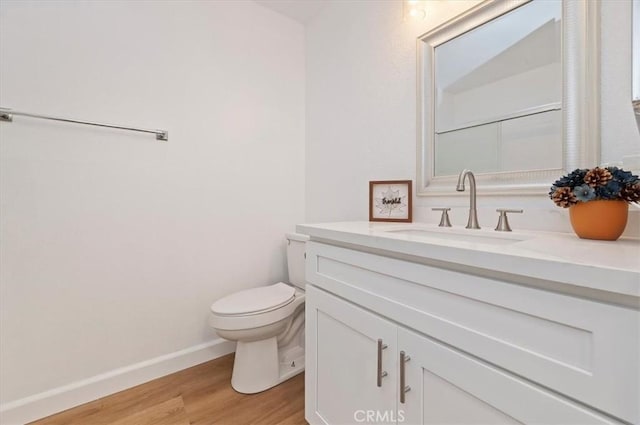 bathroom featuring wood-type flooring, toilet, and vanity