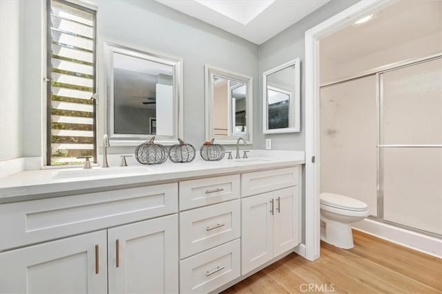 bathroom with toilet, vanity, an enclosed shower, and hardwood / wood-style flooring