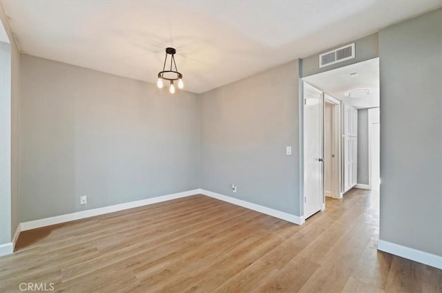 spare room with light hardwood / wood-style flooring and a chandelier