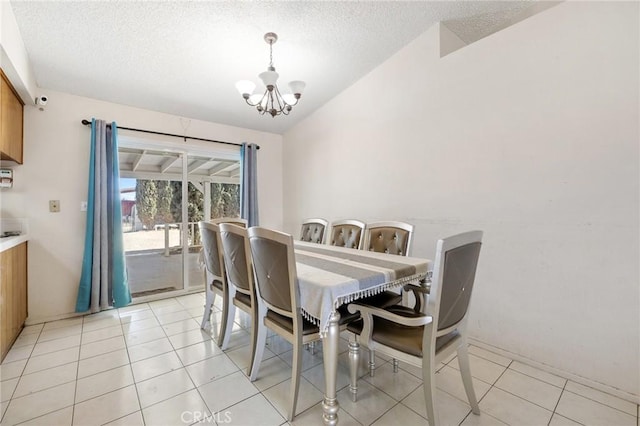 dining space with a textured ceiling, an inviting chandelier, light tile patterned floors, and vaulted ceiling