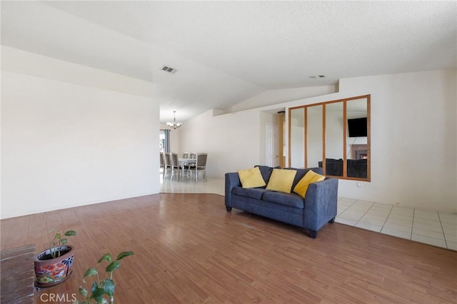 living room featuring hardwood / wood-style flooring, lofted ceiling, and a notable chandelier