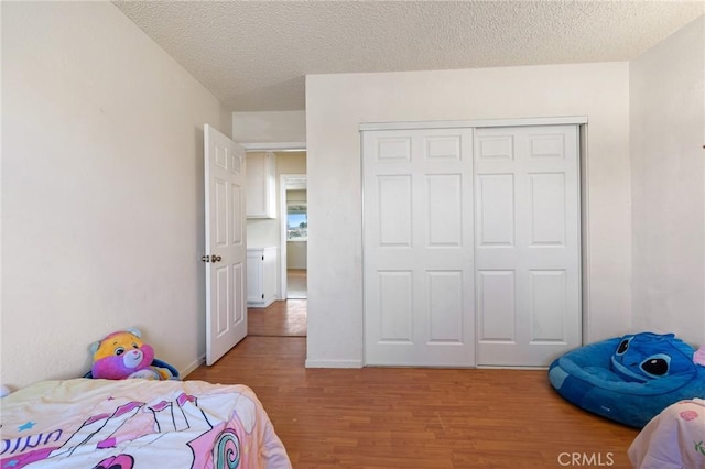 bedroom with light wood-type flooring, a closet, and a textured ceiling