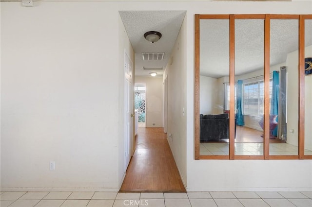 corridor with light tile patterned floors and a textured ceiling