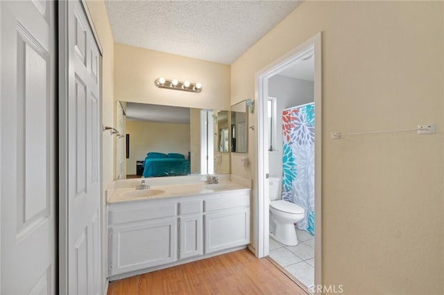 bathroom featuring toilet, vanity, a textured ceiling, and hardwood / wood-style flooring