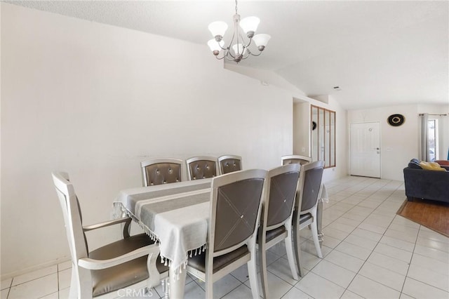 tiled dining space with lofted ceiling and a chandelier