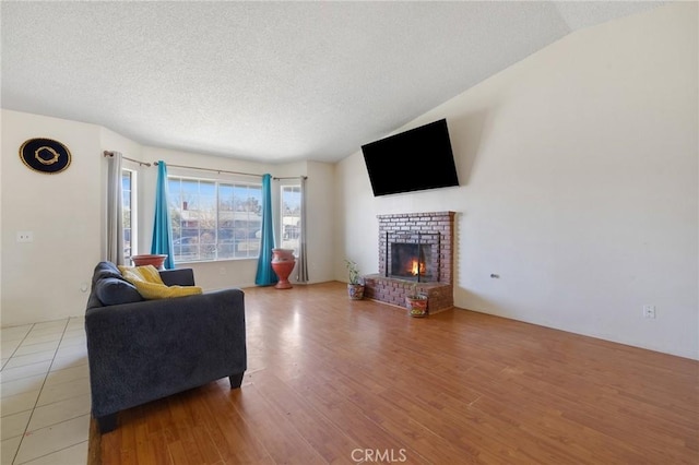 living room with a textured ceiling, a brick fireplace, lofted ceiling, and hardwood / wood-style flooring