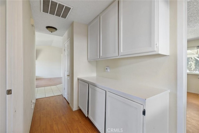 hall with light hardwood / wood-style floors and a textured ceiling