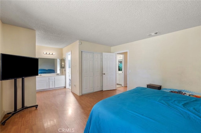 bedroom with connected bathroom, light hardwood / wood-style flooring, a closet, and a textured ceiling