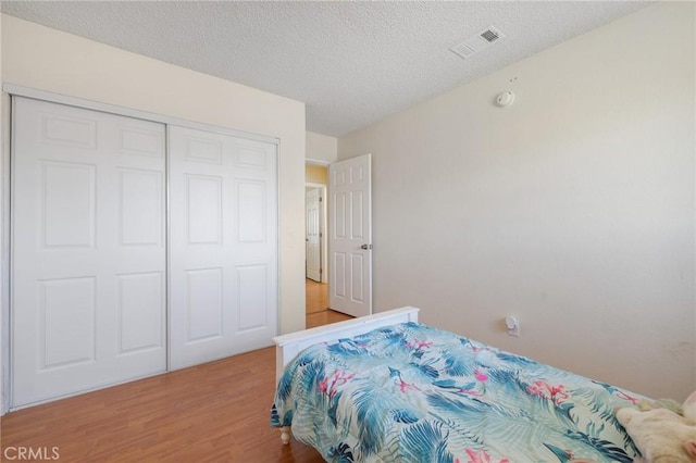 bedroom featuring a textured ceiling, a closet, and wood-type flooring