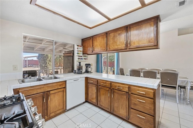 kitchen featuring tile countertops, kitchen peninsula, gas range, dishwasher, and sink