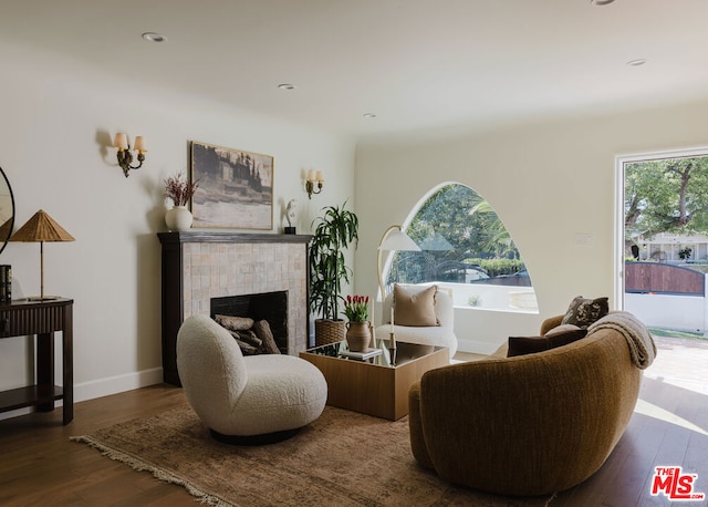 sitting room featuring a tiled fireplace and dark wood-type flooring