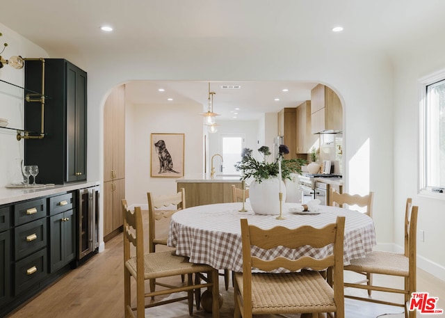 dining room featuring sink, beverage cooler, and light hardwood / wood-style flooring