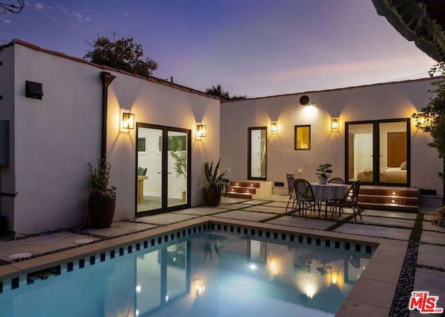 back house at dusk with a patio area and french doors