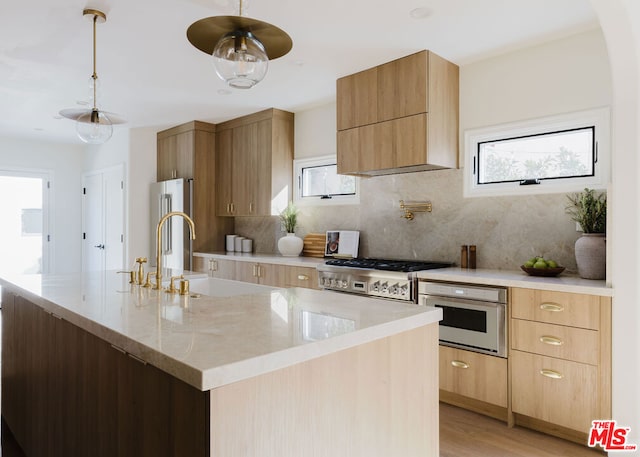 kitchen with decorative backsplash, a wealth of natural light, stainless steel appliances, and an island with sink