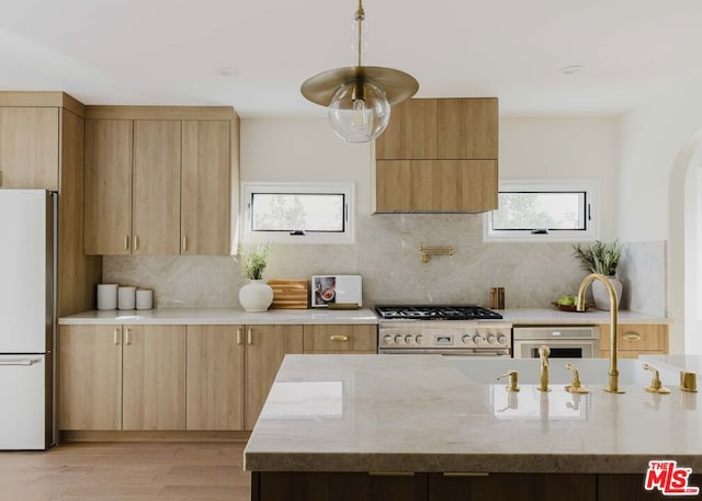 kitchen featuring stainless steel appliances, tasteful backsplash, light hardwood / wood-style floors, sink, and light stone counters