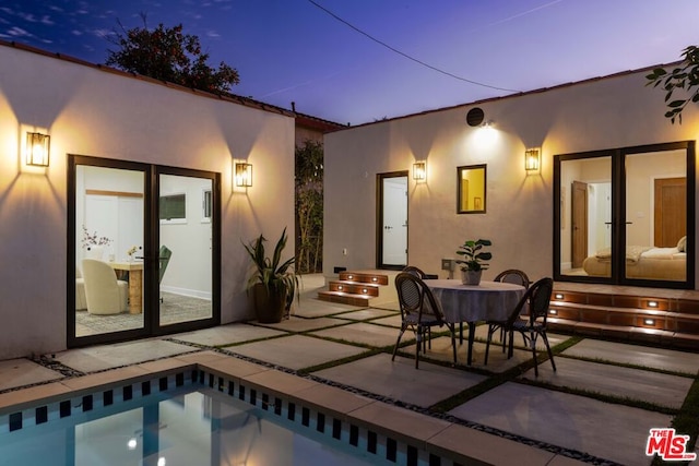 back house at dusk featuring a patio area and french doors