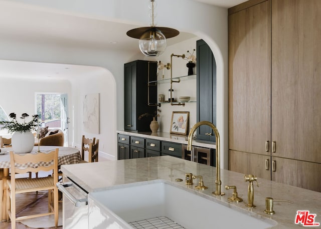 kitchen featuring decorative light fixtures, sink, dishwasher, and light stone countertops