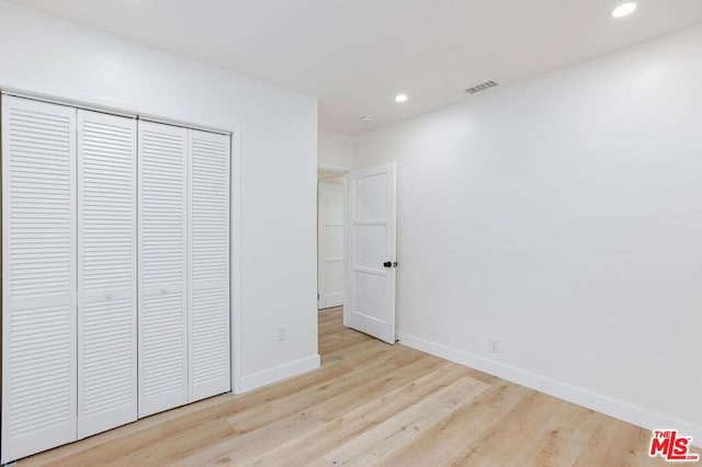 unfurnished bedroom with light wood-type flooring and a closet