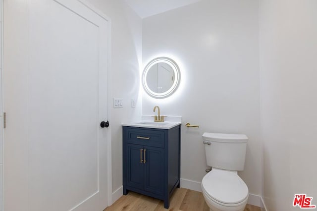 bathroom with toilet, hardwood / wood-style flooring, and vanity