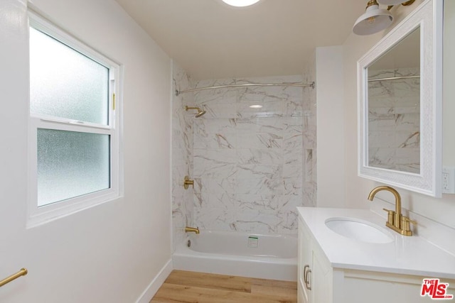 bathroom with plenty of natural light, wood-type flooring, tiled shower / bath combo, and vanity