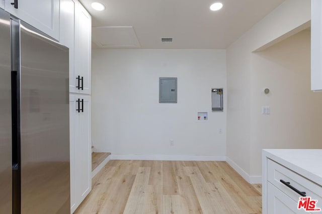 washroom featuring cabinets, electric panel, light hardwood / wood-style flooring, and hookup for a washing machine