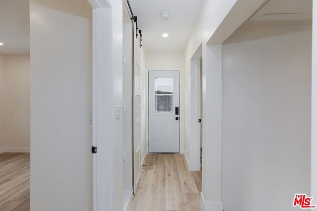 hallway featuring light hardwood / wood-style flooring and a barn door