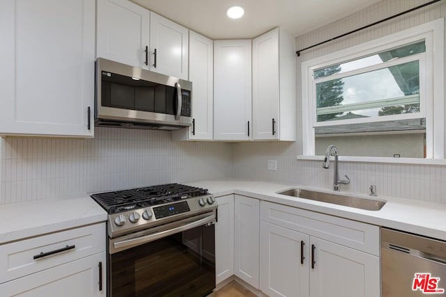 kitchen with tasteful backsplash, sink, stainless steel appliances, and white cabinetry